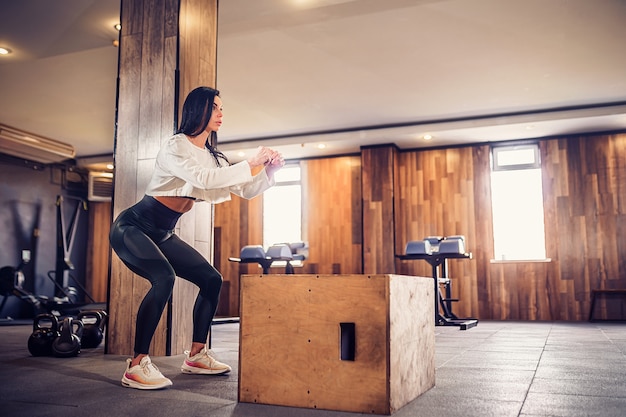 Mujer joven trabajando con una caja en el gimnasio