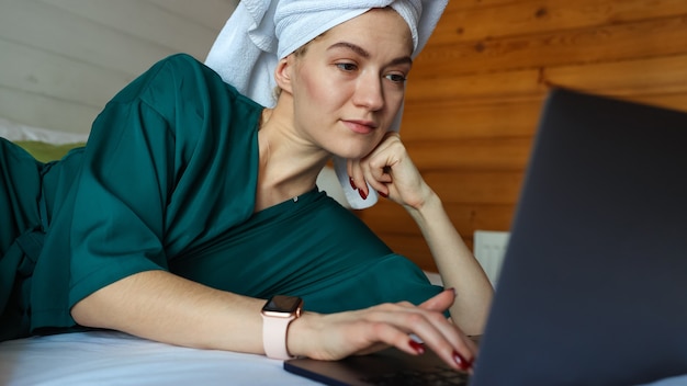 Mujer joven trabajando en la computadora después de una ducha
