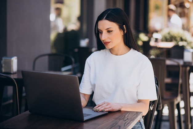 Mujer joven trabajando en un portátil en un café