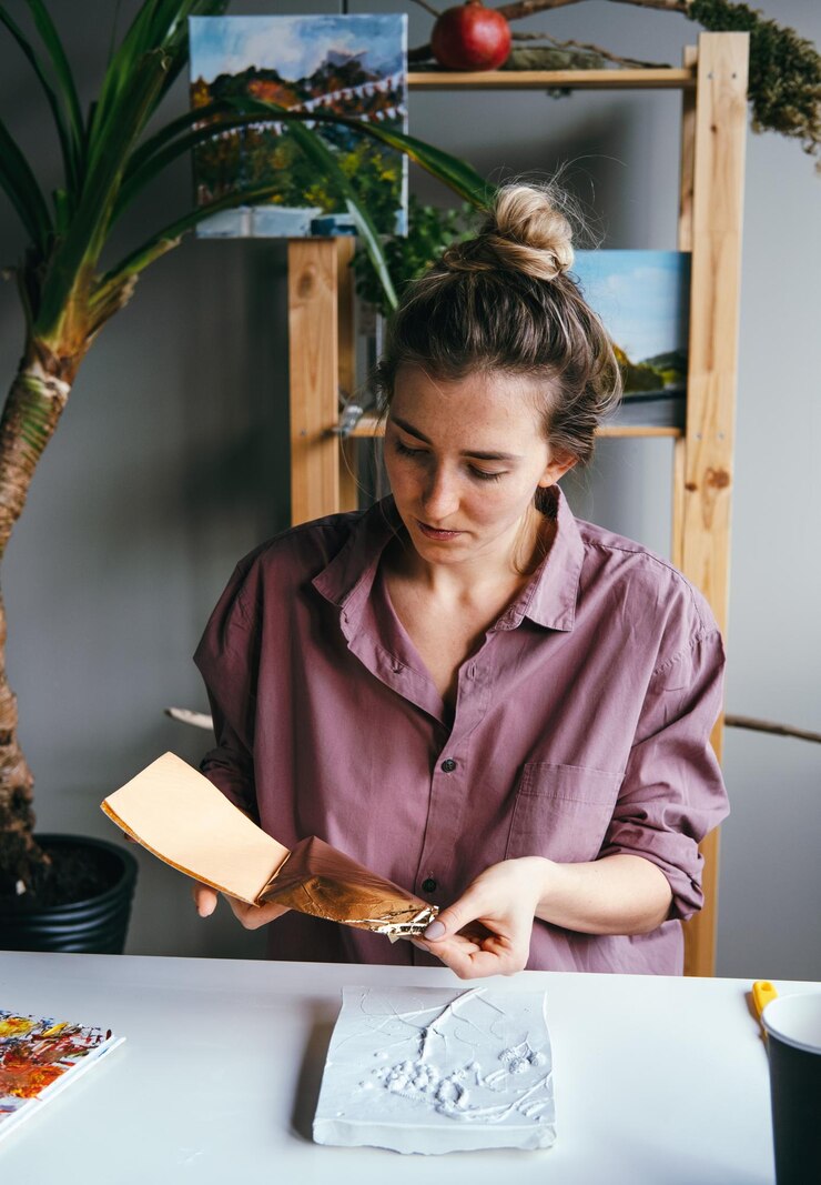 Foto mujer joven trabajando con relieve de papel dorado y yeso