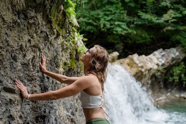 Mujer joven en traje de baño disfrutando de la cascada