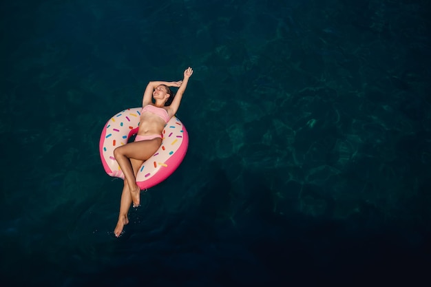 Mujer joven en traje de baño nada en un anillo inflable en el mar Concepto de vacaciones de verano