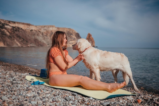 Mujer joven en traje de baño con el pelo largo practicando estiramientos al aire libre en una alfombra de yoga junto al mar en un