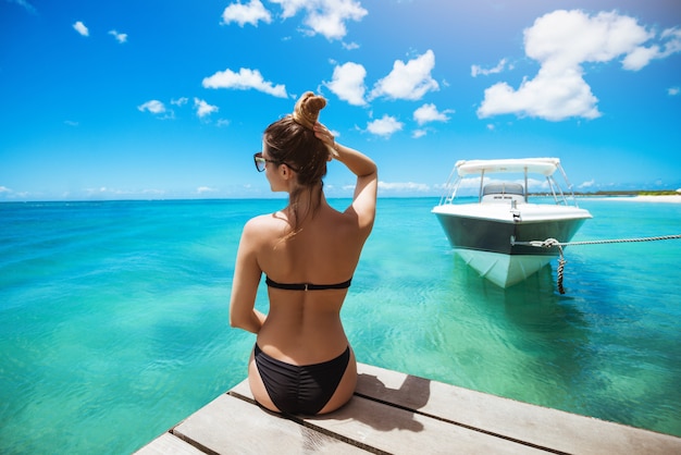 Mujer joven en traje de baño tomando el sol acumulando cabello mirando lejos