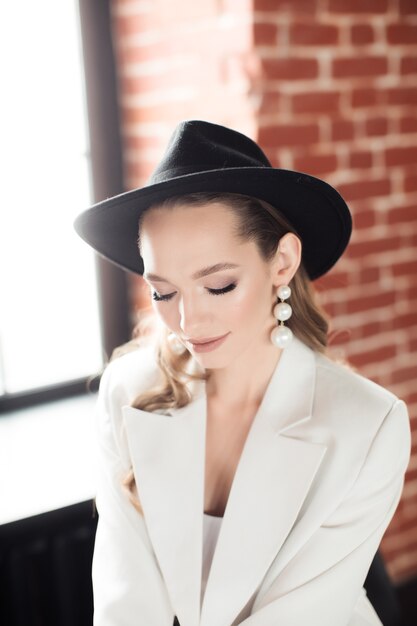 Mujer joven con un traje blanco y un sombrero negro