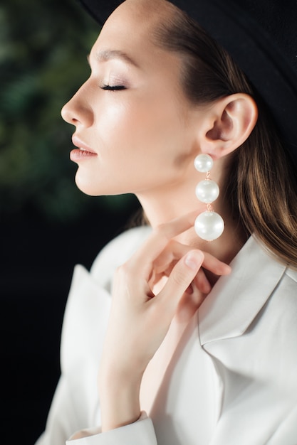 Mujer joven con un traje blanco y un sombrero negro