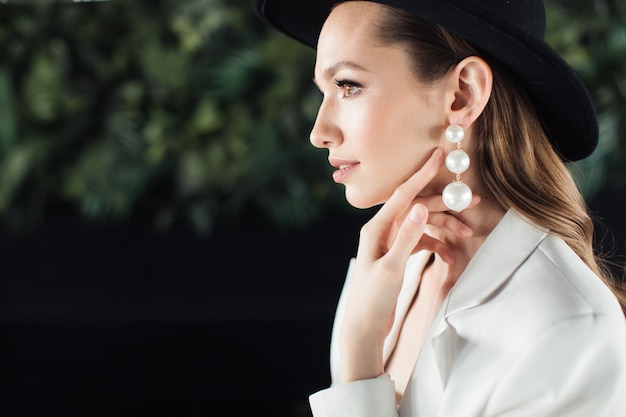 Mujer joven con un traje blanco y un sombrero negro