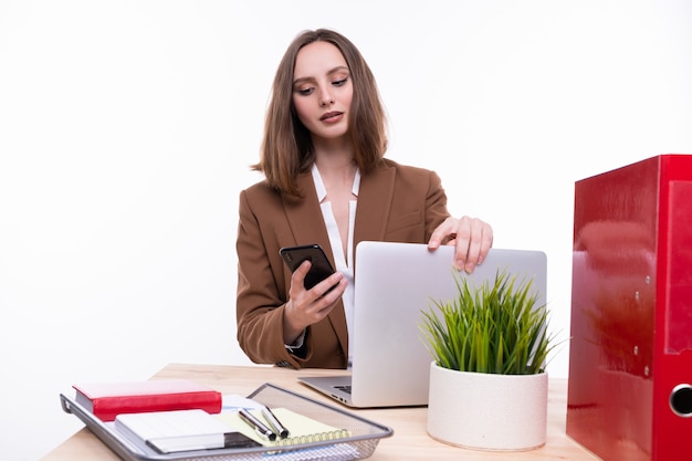 Una mujer joven en un traje de negocios está trabajando en una computadora portátil