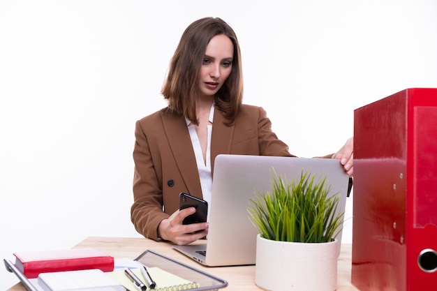 Una mujer joven en un traje de negocios trabajando en una computadora portátil sobre un fondo blanco. Aislado