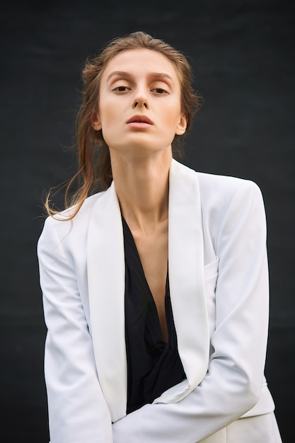 Mujer joven en un traje negro y una chaqueta blanca