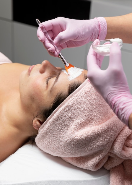 Mujer joven con un tratamiento facial en el salón de belleza