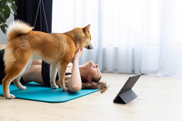 Mujer joven tratando de hacer ejercicio junto a su perro