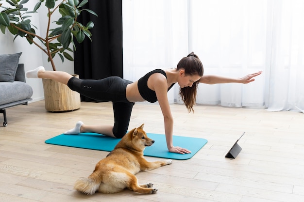 Foto mujer joven tratando de hacer ejercicio junto a su perro