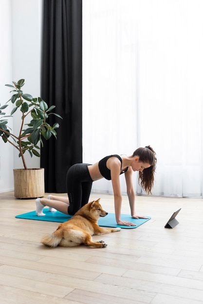 Foto mujer joven tratando de hacer ejercicio junto a su perro