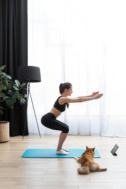 Foto mujer joven tratando de hacer ejercicio junto a su perro