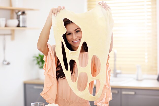 Mujer joven tratando de hacer pierogi en la cocina