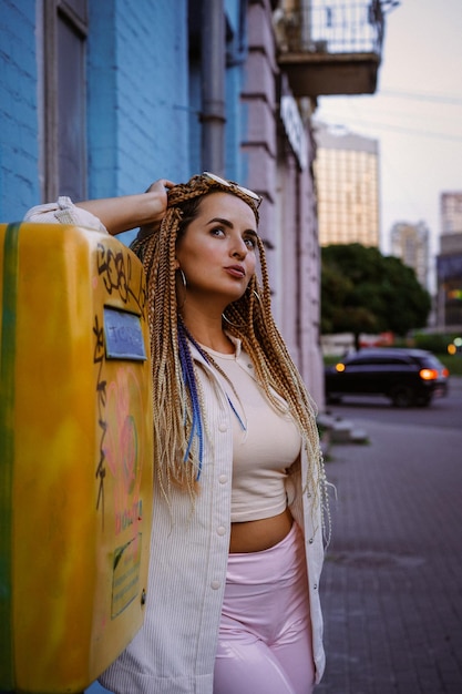 mujer joven con trenzas afro zizi y maquillaje brillante en una gran ciudad, retrato. Peinados con trenzas zizi.