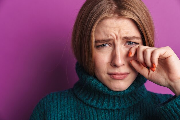 mujer joven triste posando aislada sobre la pared púrpura.