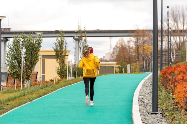 Mujer joven trotar en el parque de otoño a lo largo del terraplén