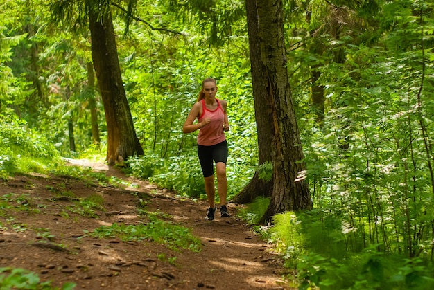 Mujer joven trotar por un sendero en un bosque de montaña