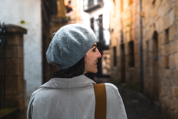 Mujer joven turista caucásica visitando calles estrechas de un casco antiguo.