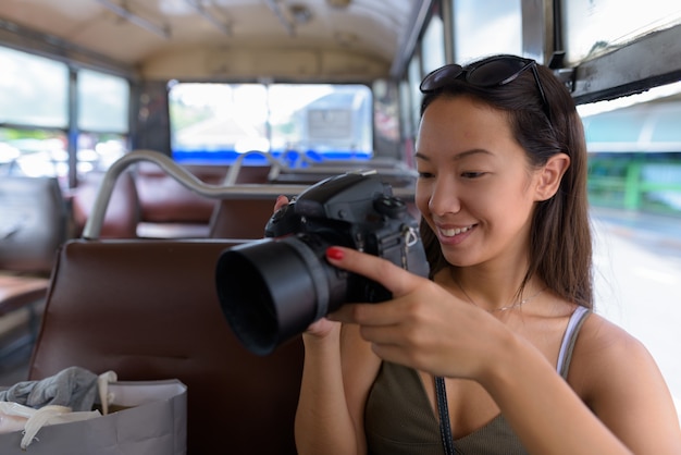 Mujer joven turista sentada en el autobús mientras usa una cámara DSLR