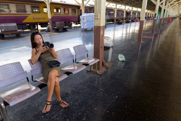 Mujer joven turista sentado y con cámara DSLR