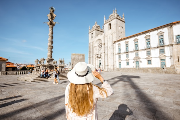 Mujer joven turista en sombrero para el sol de pie delante de la catedral principal de la ciudad de Oporto en Portugal