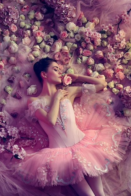 Mujer joven en tutú de ballet rosa rodeado de flores