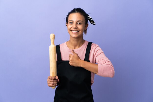 Mujer joven en uniforme de chef dando un pulgar hacia arriba gesto