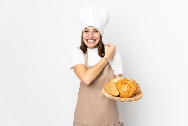 Mujer joven en uniforme de chef en la pared blanca celebrando una victoria