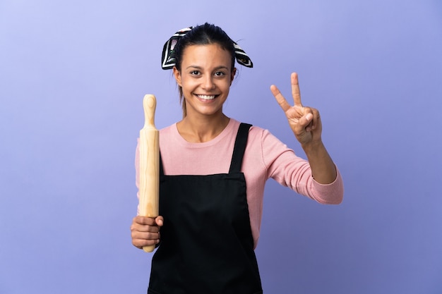 Mujer joven en uniforme de chef sonriendo y mostrando el signo de la victoria