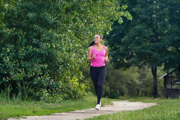 Mujer joven en uniforme deportivo corre en un parque