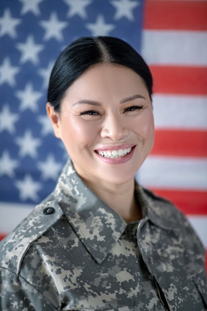 Foto mujer joven en uniforme militar con la bandera americana