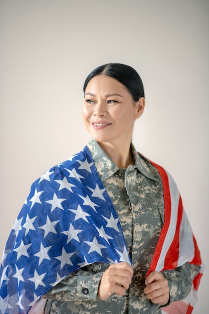 Mujer joven en uniforme militar con la bandera americana