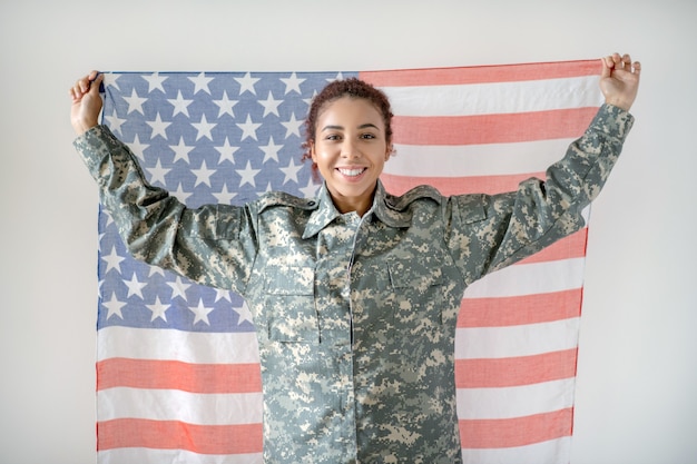 Mujer joven en uniforme militar sosteniendo la bandera americana