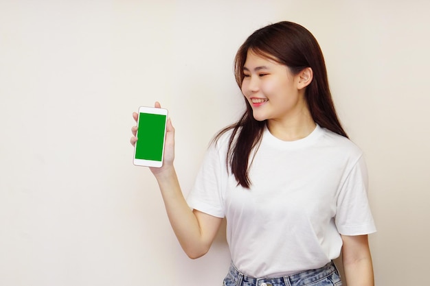 Una mujer joven usa una camiseta blanca con un teléfono móvil de pantalla verde