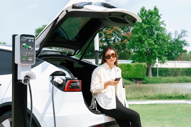 Foto mujer joven usa su teléfono inteligente para pagar la electricidad de su coche