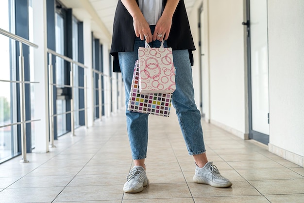 Mujer joven usa tela con estilo con bolsas de compras en el centro comercial ventas y descuentos del viernes negro