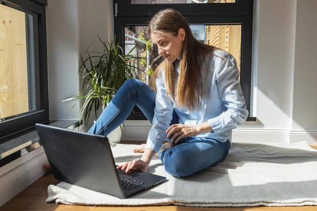 Foto mujer joven usando una computadora portátil en casa