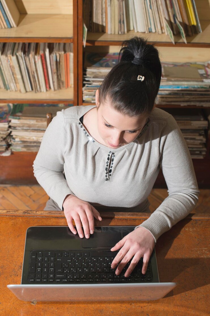 Foto mujer joven usando una computadora portátil en la mesa de la biblioteca