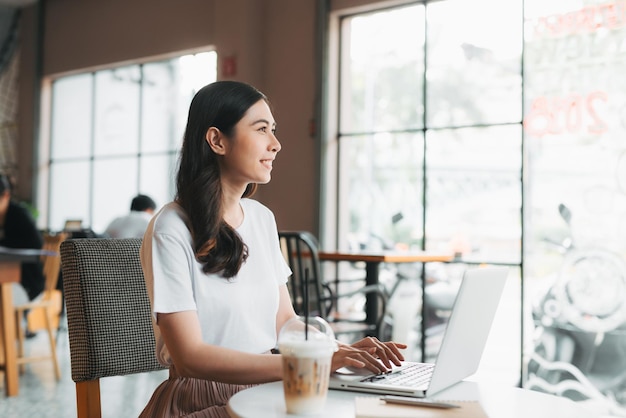 Mujer joven usando una computadora portátil mientras está sentada en una cafetería