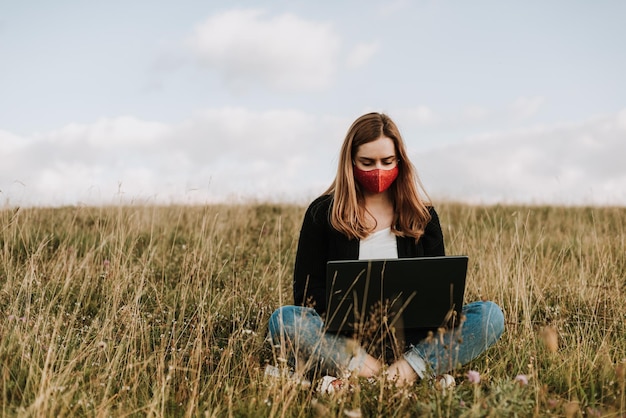 Mujer joven usando una computadora portátil mientras está sentada en el campo