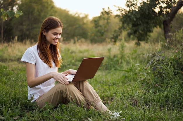 Mujer joven usando una computadora portátil mientras está sentada en el campo