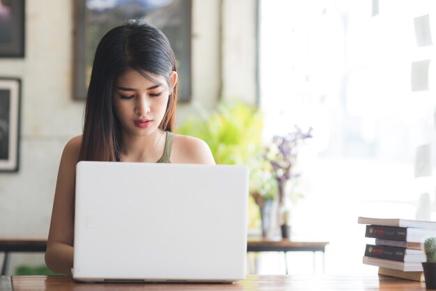 Mujer joven usando una computadora portátil mientras está sentada en la mesa