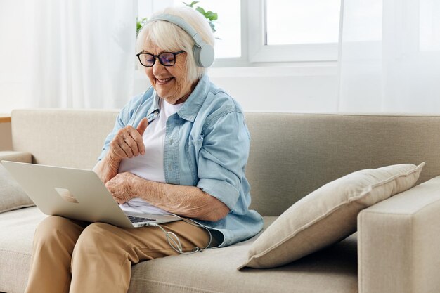 Mujer joven usando una computadora portátil mientras está sentada en el sofá en casa