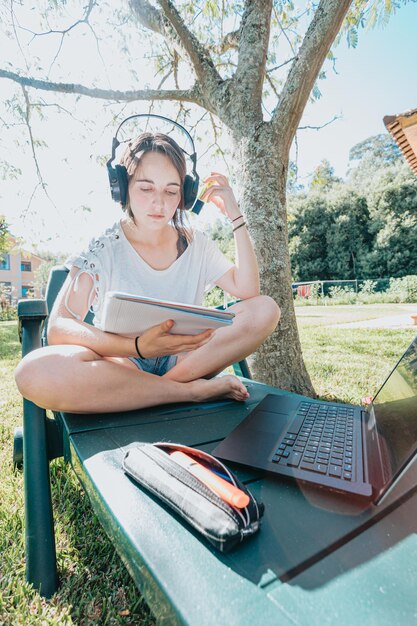 Foto mujer joven usando una computadora portátil mientras está sentada en el campo