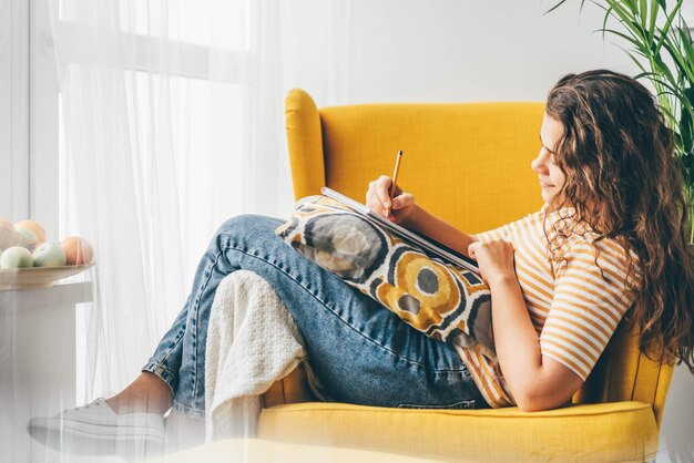 Foto mujer joven usando una computadora portátil mientras está sentada en el sofá en casa