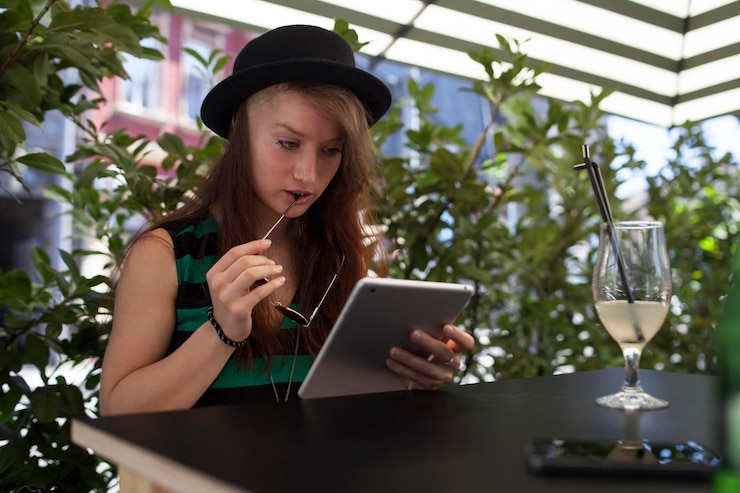 Foto mujer joven usando una tableta digital en la mesa contra las plantas
