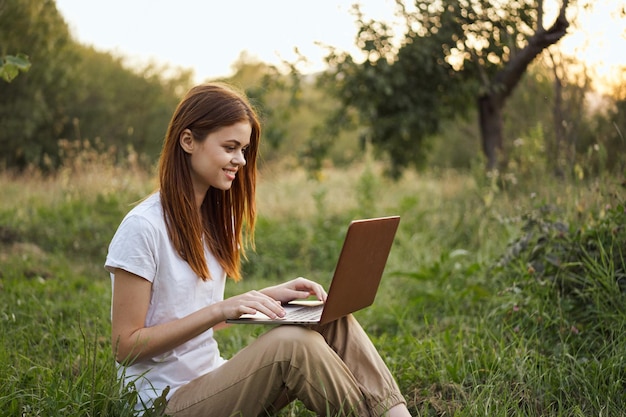 Mujer joven usando una tableta digital mientras está sentada en el campo